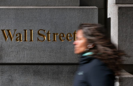 A woman walks down Wall Street in New York