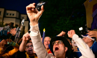 Des partisans du chef du parti AUR George Simion saluent sa victoire au premier tour de la présidentielle, le 4 mai 2025 à Bucarest ( AFP / Daniel MIHAILESCU )